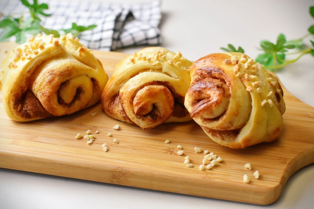 Freshly baked sourdough cinnamon rolls with a golden brown crust, soft and fluffy on the inside, dusted with powdered sugar, placed on a rustic wooden table.