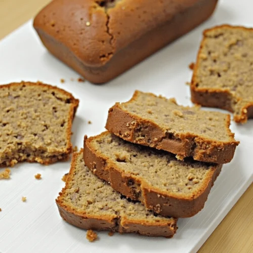 "Slice of cake mix banana bread with honey drizzle, banana slices, and coffee, set on a wooden table."