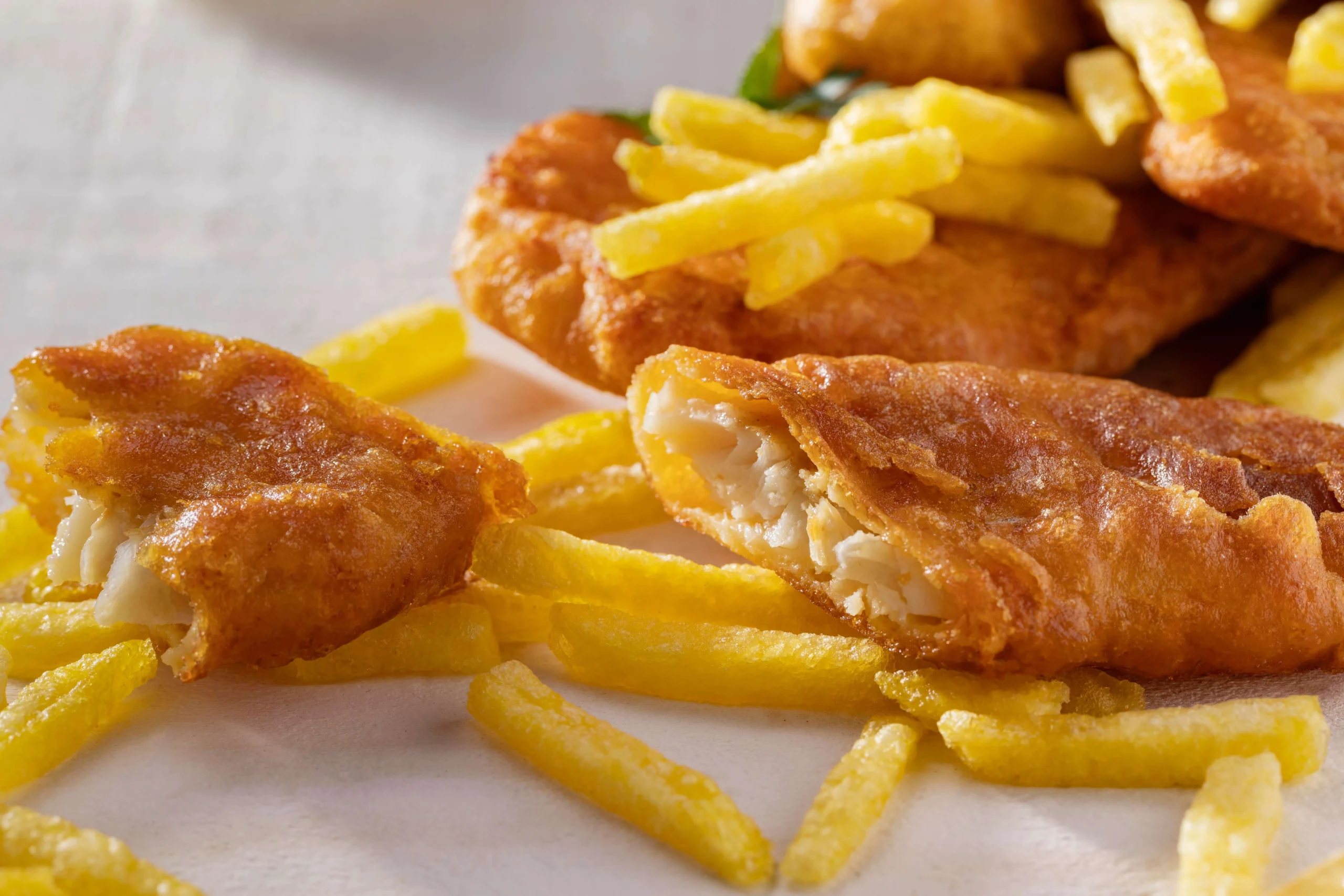 A realistic image of gluten-free fish and chips with crispy fish fillets, golden fries, tartar sauce, and lemon wedges.