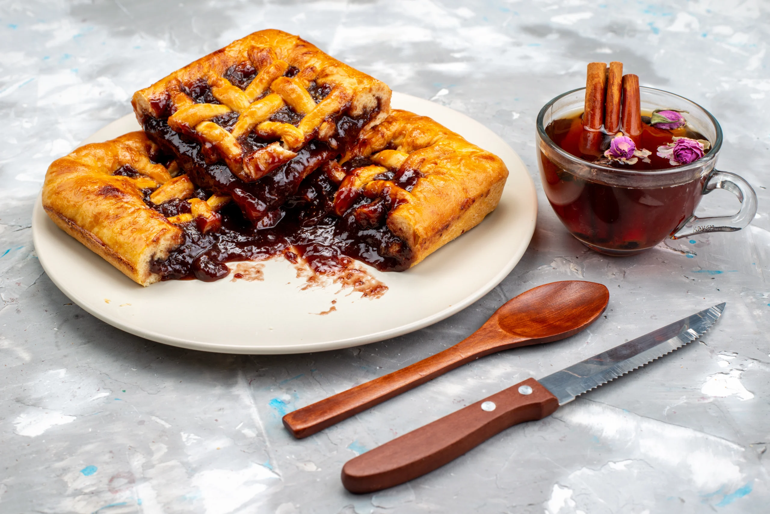 Freshly baked cinnamon roll apple pie with golden-brown crust, gooey apple filling, and white glaze, surrounded by apple slices on a wooden table